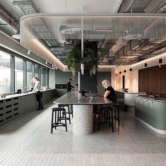 an office with two people working on their laptops in the middle of the room