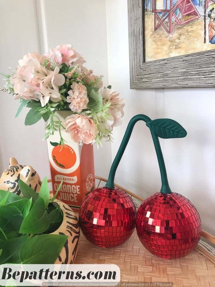 two red disco ball vases sitting on top of a table next to a flower pot