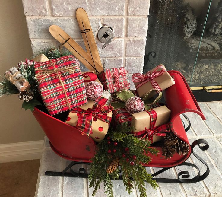 a red sleigh filled with presents and wooden spoons next to a fireplace