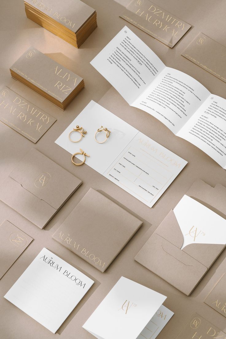 the wedding stationery is laid out on top of each other with gold rings and napkins