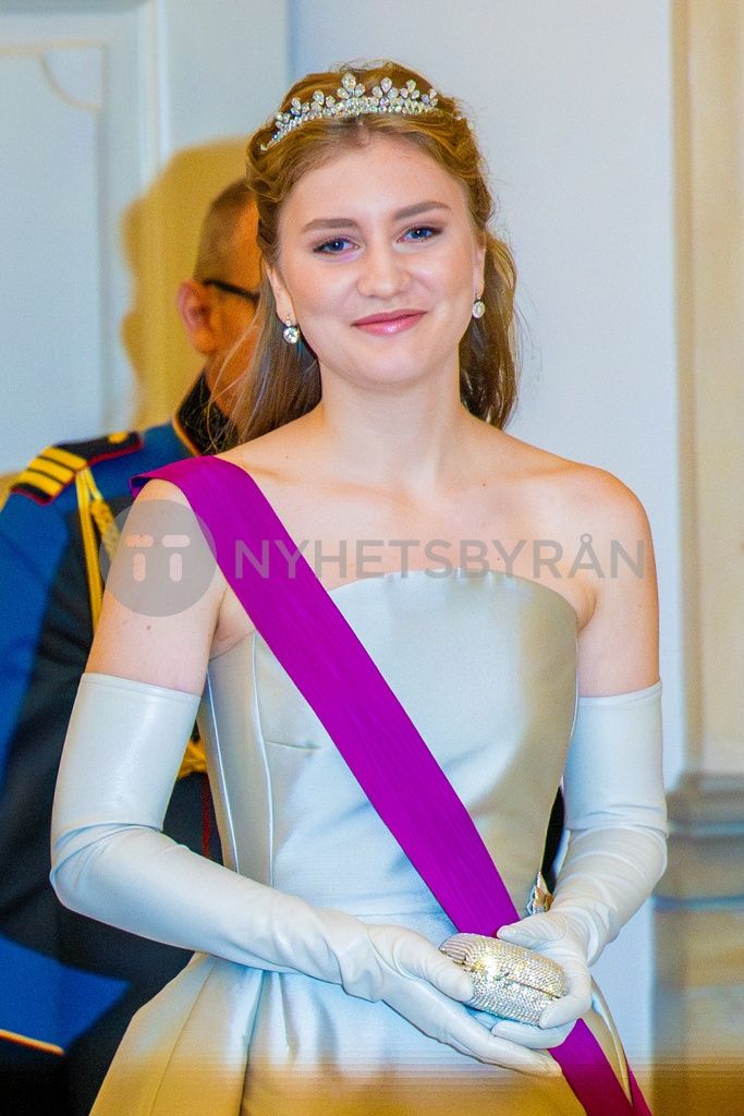 a woman wearing a tiara and holding a purple sash in front of other people