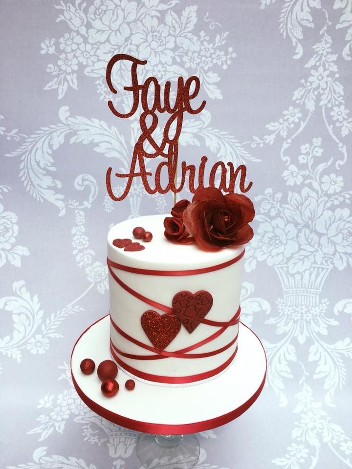 a white cake with red decorations on top and the word love is spelled in cursive writing