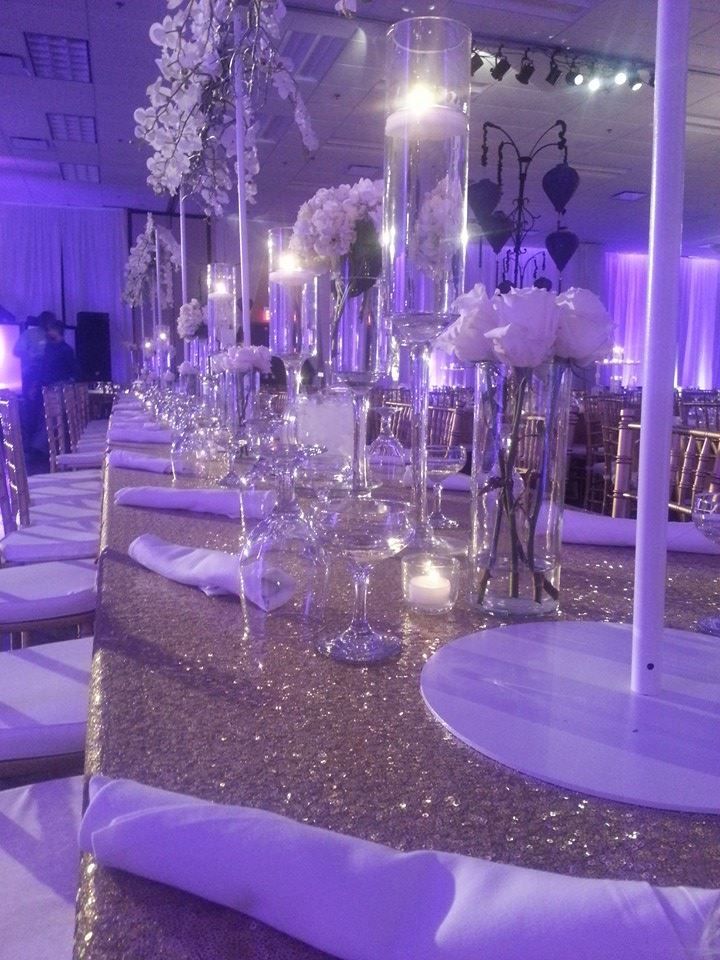 the tables are set up with white flowers and silver sequins for an elegant wedding reception