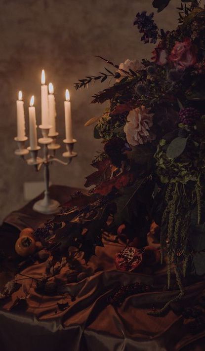 three candles are lit in front of a table with flowers and other items on it