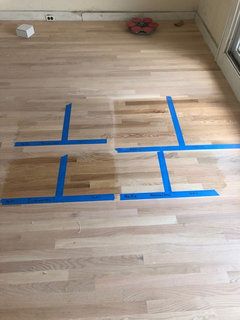 an unfinished floor with blue tape on it and a window in the background that is being installed