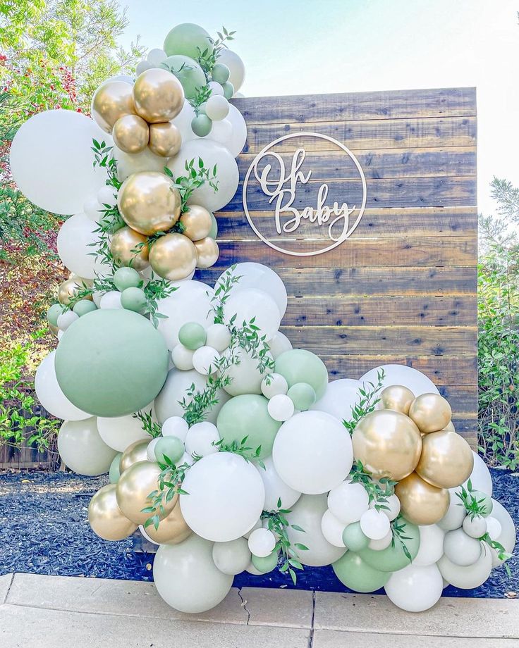 balloons and greenery are arranged on the side of a sign