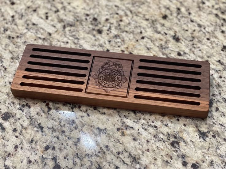 a wooden grate sitting on top of a granite counter next to a bottle opener