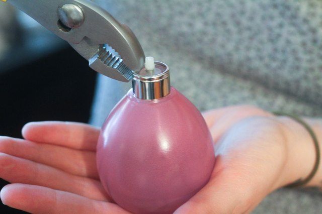 a person holding a small pink bottle with a corkscrew on it