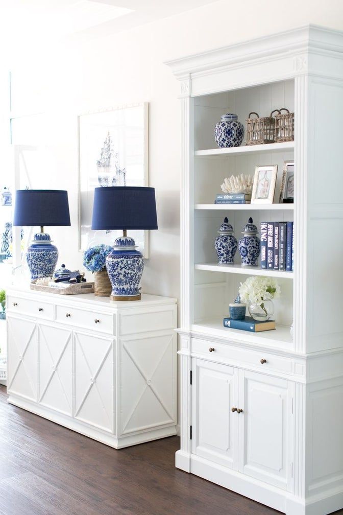 a white bookcase with blue and white vases sitting on it's sides