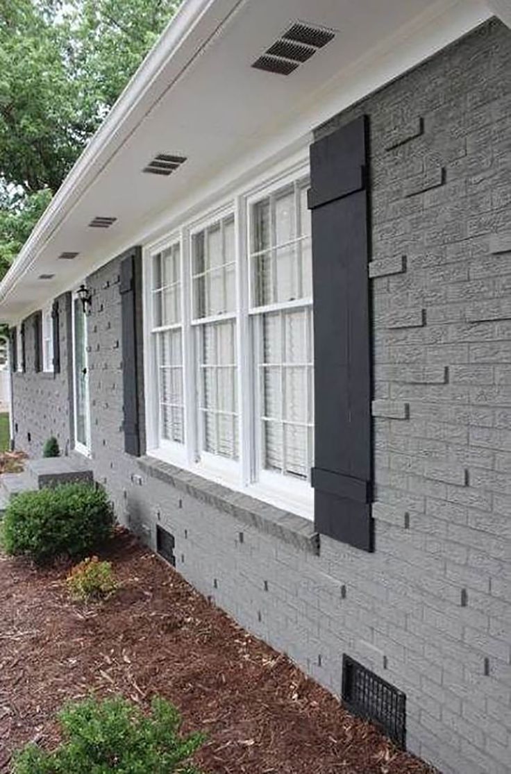 the side of a house with black shutters and white trim on it's windows