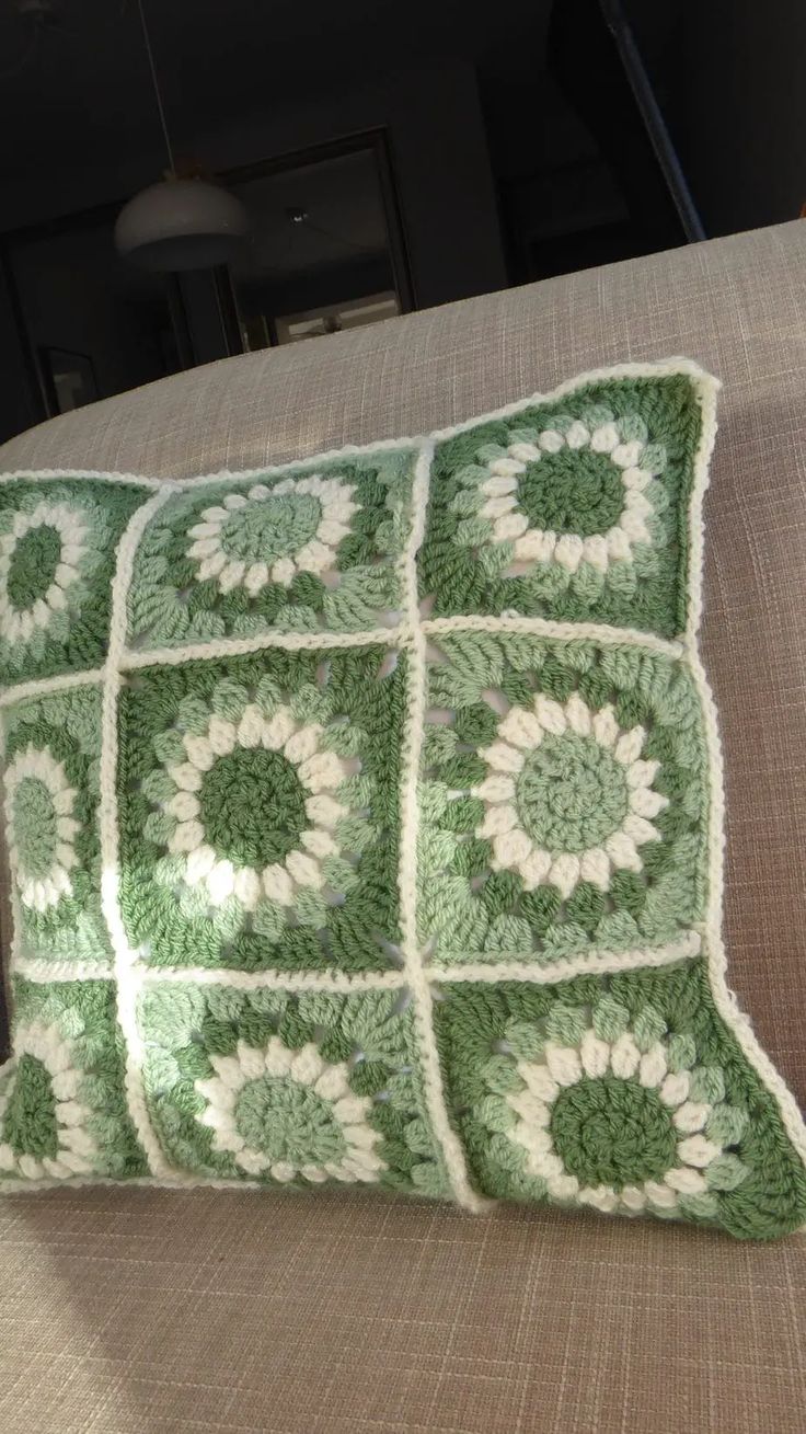 a green and white crocheted pillow sitting on top of a couch