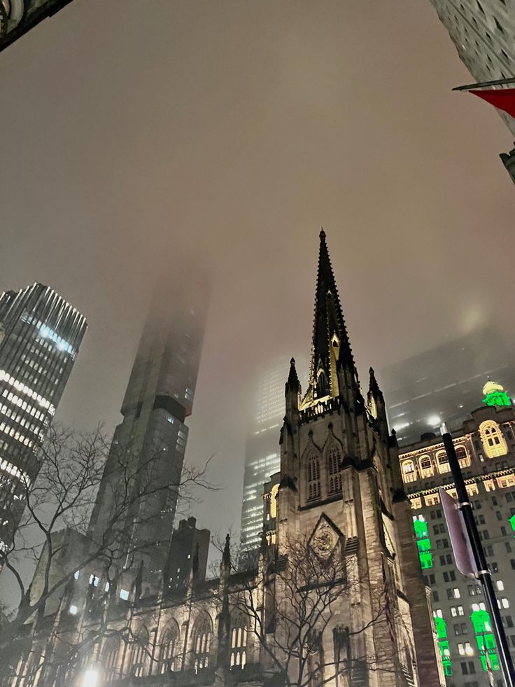 an image of a city at night with tall buildings in the foreground and fog on the ground