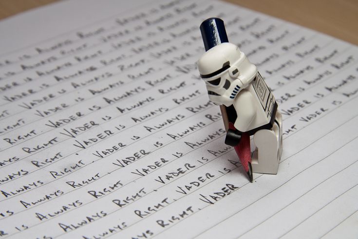 a star wars lego figure sitting on top of a piece of paper with writing in it