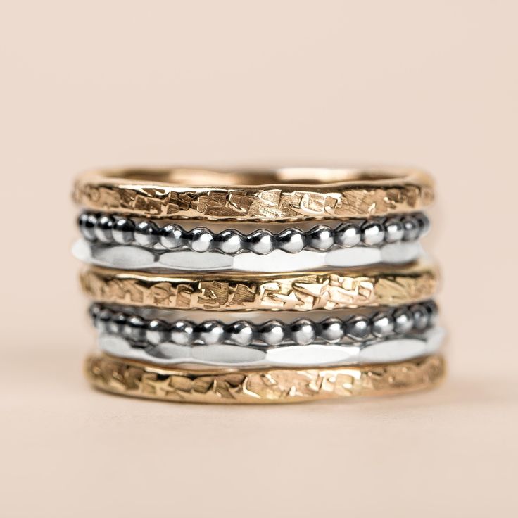 Introducing The Demi Stack, a set of seven unique and beautiful stacking rings that are perfect for making a bold statement. Made with mixed metals in gold fill and sterling silver, each ring features a different texture, from raw silk to mirror hammered. Mix and match them to create your own unique look. Whether you're dressing up or dressing down, these rings are sure to add a touch of edge and coolness to any outfit. USA sizes 4-12. Made with high quality materials, these rings are built to last. The set includes 3 14K yellow gold fill heavy weight "Raw Silk" stackers, 2 sterling silver "Dot" stackers, and 2 Sterling silver "Mirror" stackers. So whatever your style, you're sure to find the perfect combination with this set. PRODUCT DETAILS & MEASUREMENTS: - 100% Handmade in the USA. - M Fusion Style Stackable Round Jewelry, Fusion Style Stackable Ring Jewelry, Unique Stackable Rings For Everyday, Fusion Style Stackable Round Rings, Unique Hammered Stackable Rings For Promise, Stackable Sterling Silver Fusion Rings, Unique Hammered Stackable Rings For Anniversary, Rings In Gold, Ring Bands