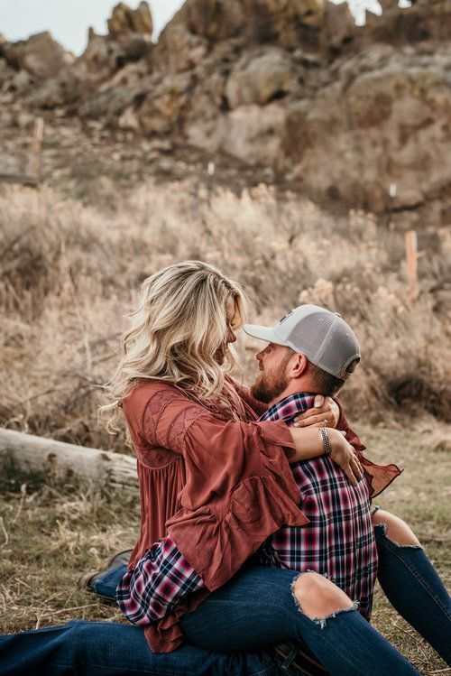 a man and woman sitting on the ground with their arms around each other as they cuddle