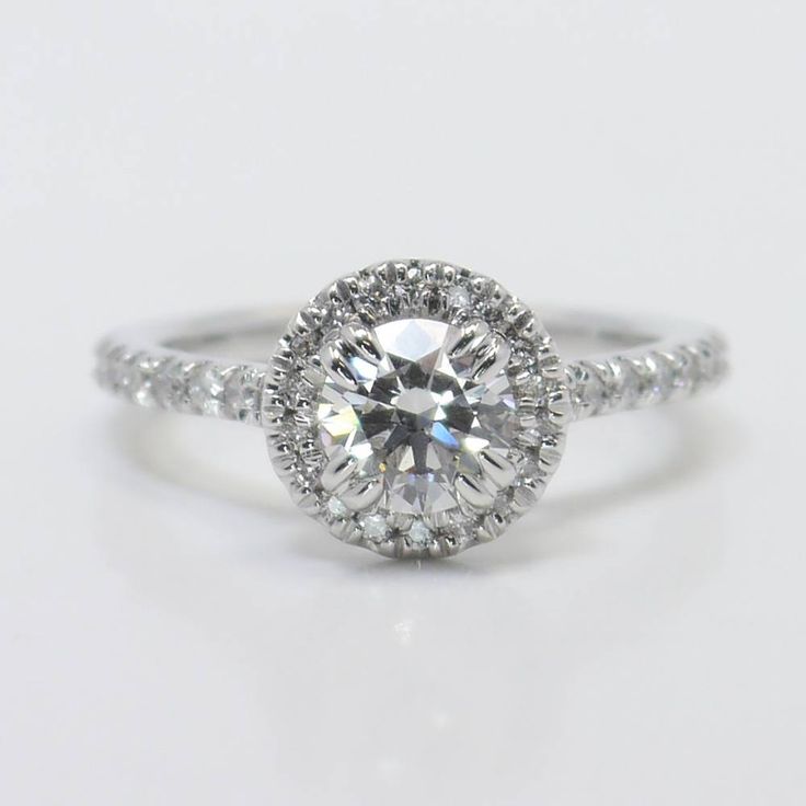 an engagement ring with a round cut diamond in the center and pave set shoulders