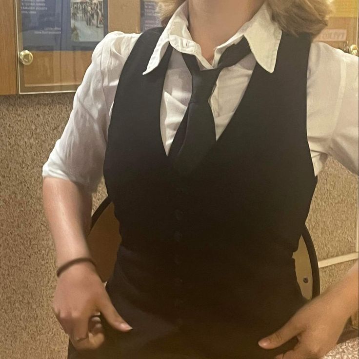 a woman with blonde hair wearing a black vest and tie