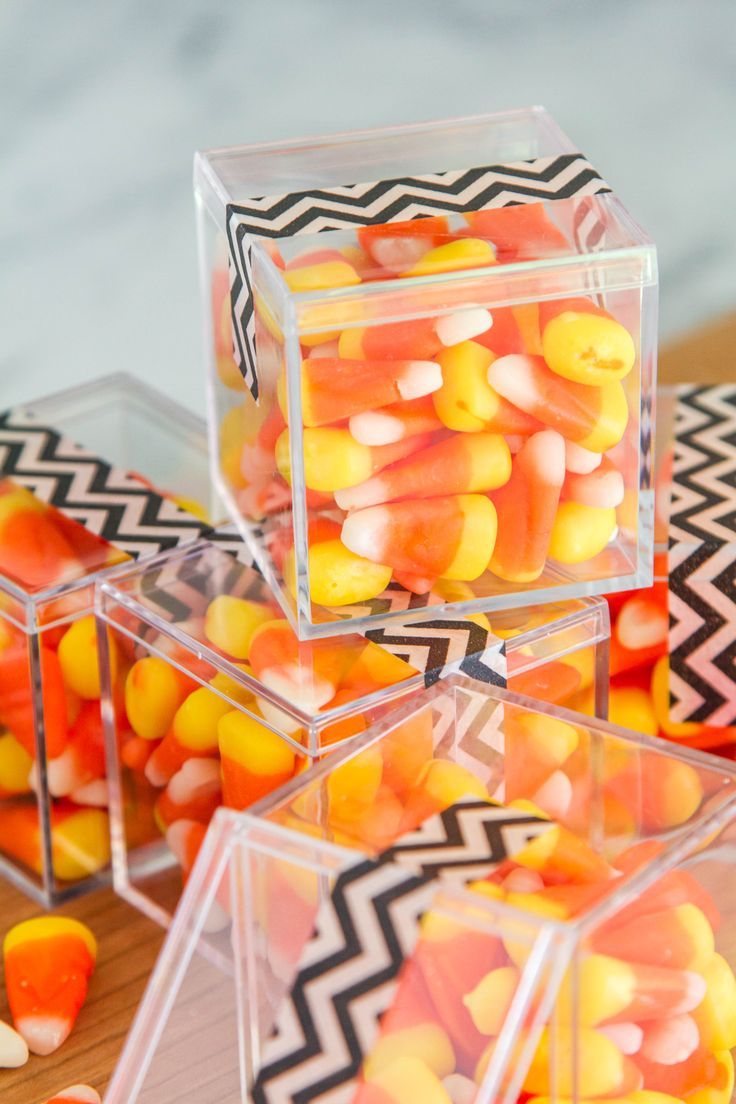 three clear boxes filled with candy corn on top of a table