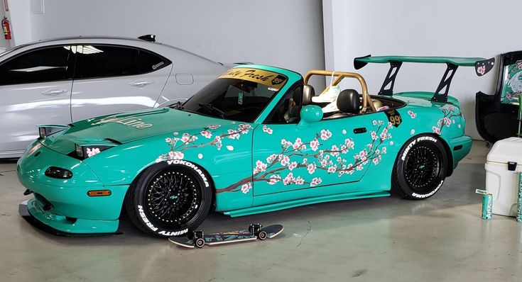 a blue car with flowers painted on the side is parked in a garage next to two other cars