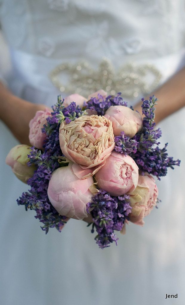 a bride holding a bouquet of pink and purple flowers on her wedding day in front of the camera