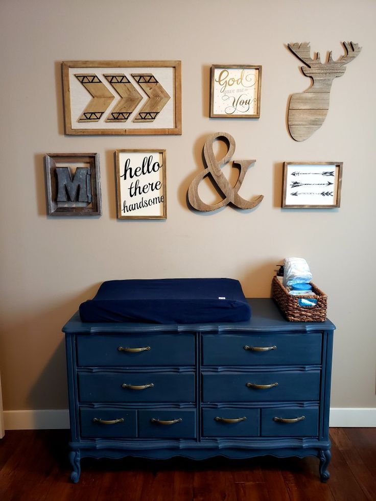 a blue dresser sitting in front of a wall filled with pictures and framed art on it