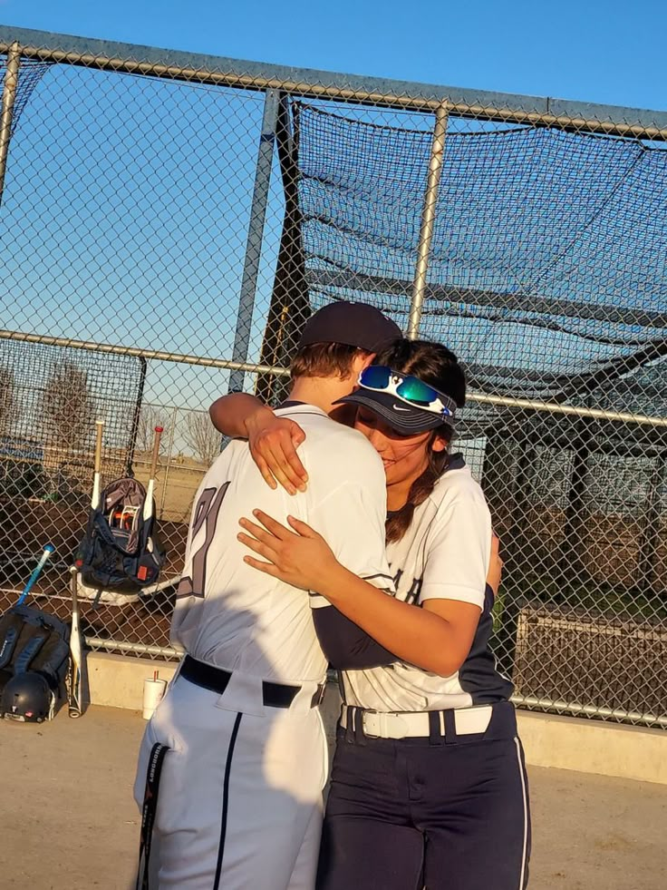 two baseball players hugging each other in front of a fence