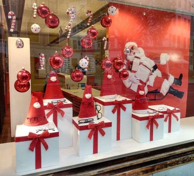 a window display with christmas decorations and santas in red hats on top of white boxes