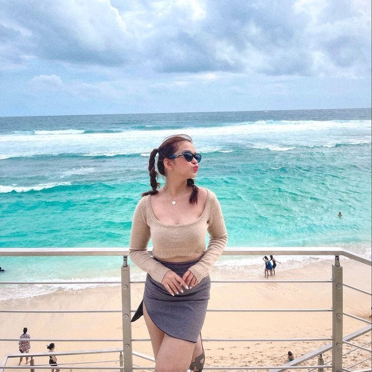 a woman standing on top of a beach next to the ocean