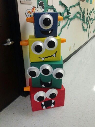 a stack of toy blocks with googly eyes and mouths on them in front of a door