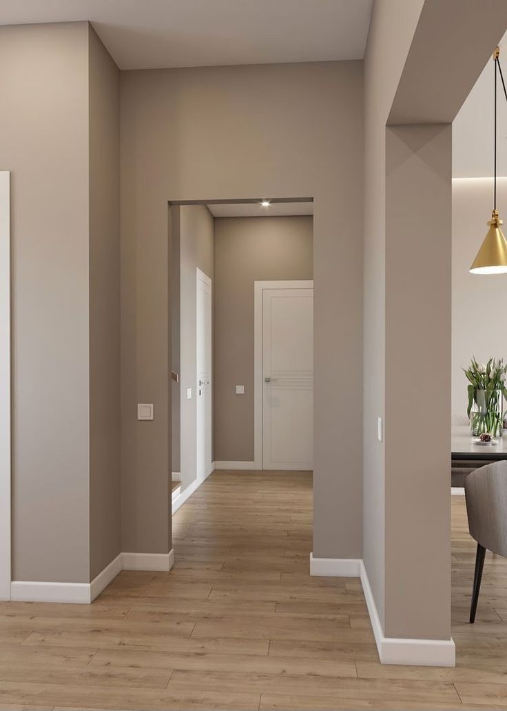 an empty living room and dining room with hard wood flooring, beige walls and white trim