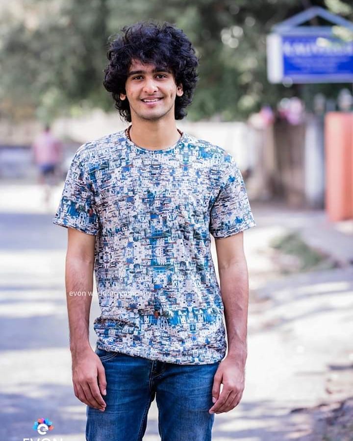 a man standing on the street with his hands in his pockets and smiling at the camera