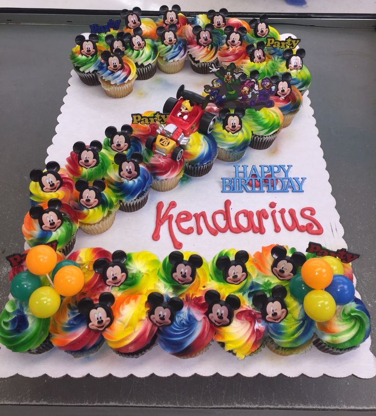 a birthday cake with mickey mouse cupcakes on it