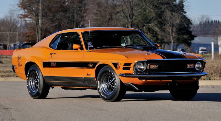 an orange muscle car is parked on the street