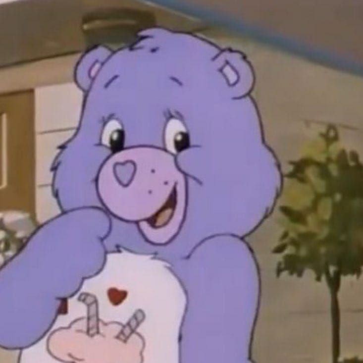 a purple teddy bear holding a cake in its paws and smiling at the camera,