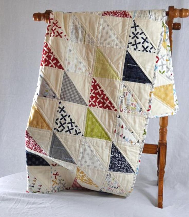 a quilted blanket sitting on top of a wooden chair next to a white wall