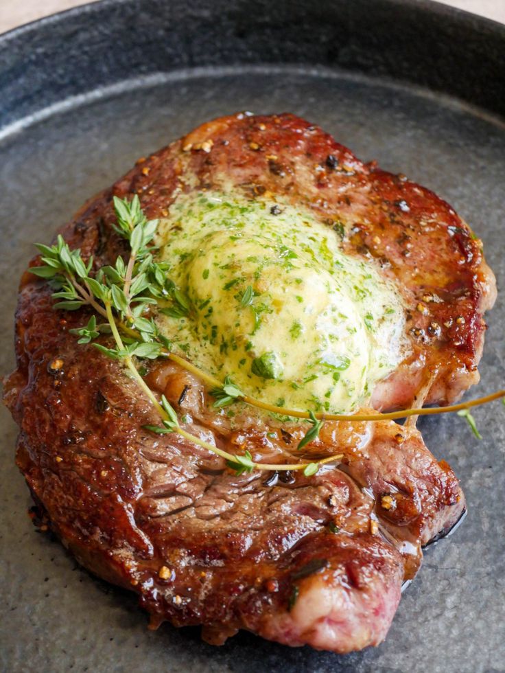 a piece of meat with an egg in the center on a black plate, garnished with herbs