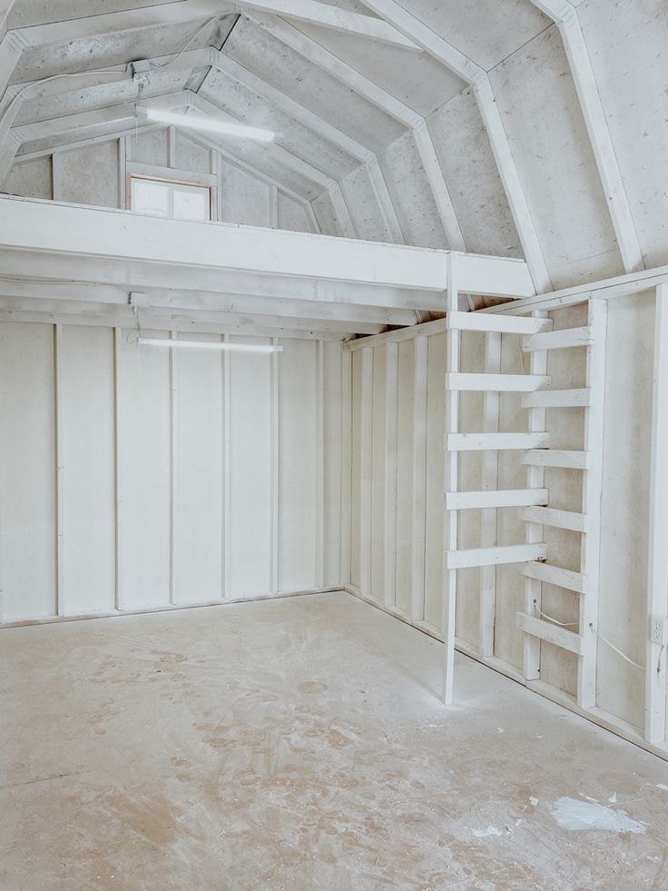 an empty room with white walls and ladders on the ceiling, is shown in this image