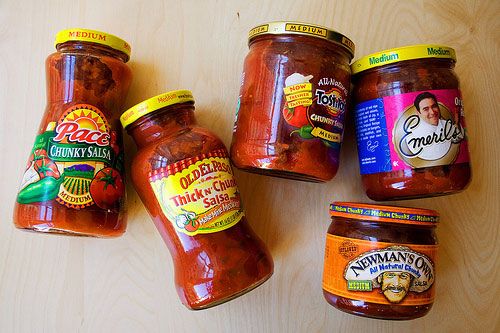 six jars of tomato sauce sitting on top of a wooden table