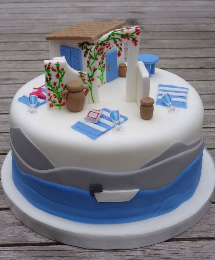 a white cake with blue and grey frosting on a wooden table next to a house