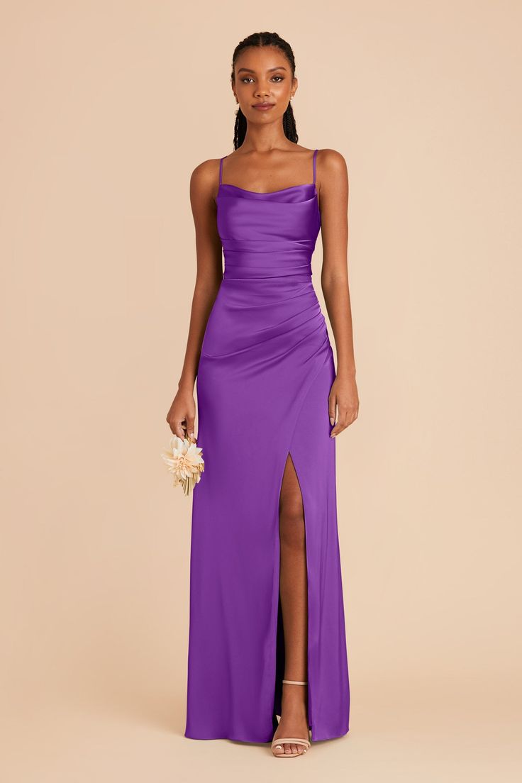 a woman in a long purple dress with one leg slited and the other side split open