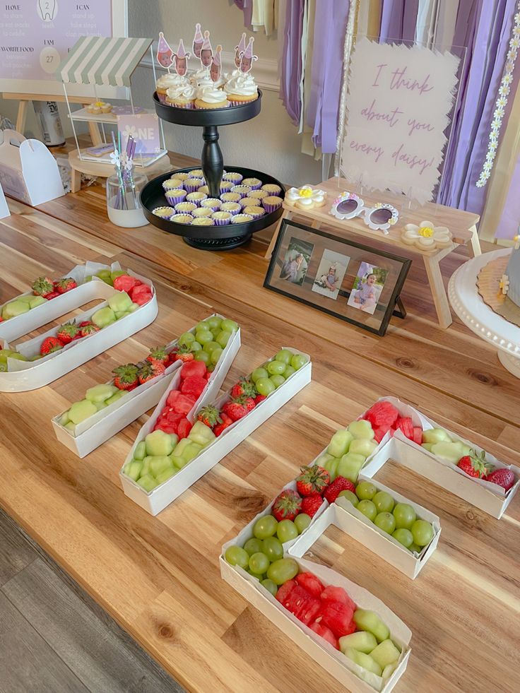 a table topped with lots of trays filled with different types of fruits and veggies