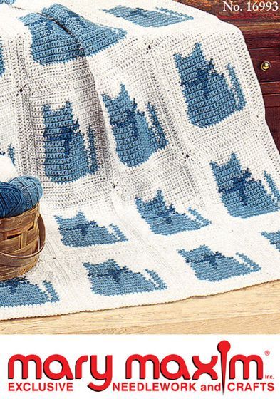 a crocheted blue and white blanket on top of a wooden table next to a pair of shoes