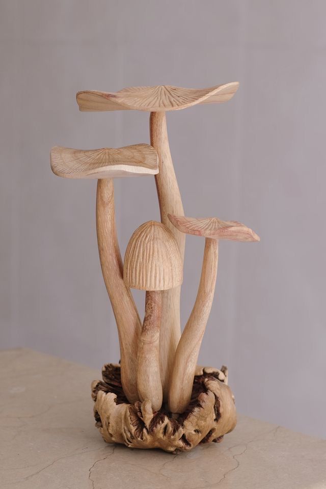 a wooden sculpture with three mushrooms on top of it