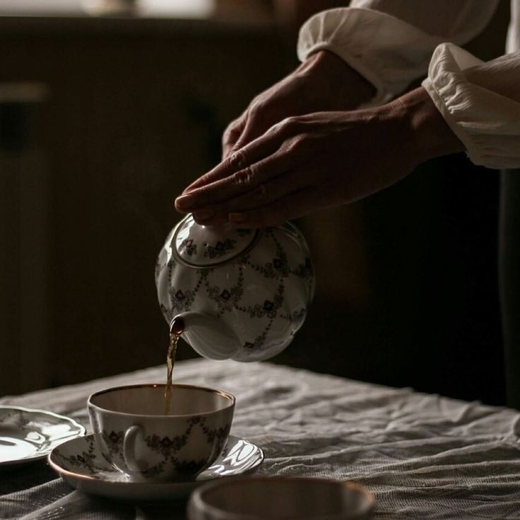 a person pouring tea into a cup on a table