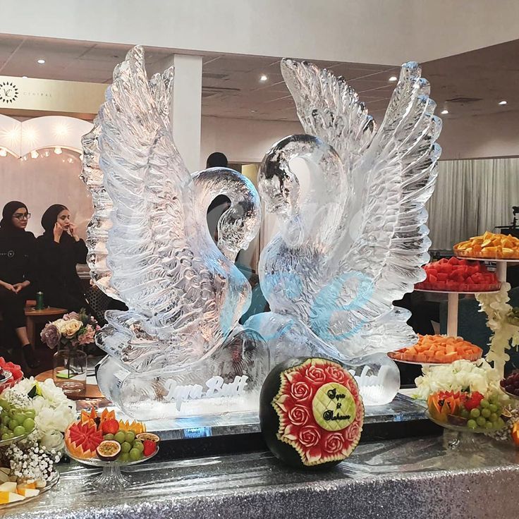 two ice swans are on display in front of other foods and people looking at them