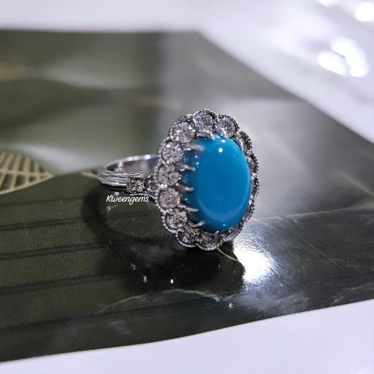 a blue stone ring sitting on top of a black table next to a green book