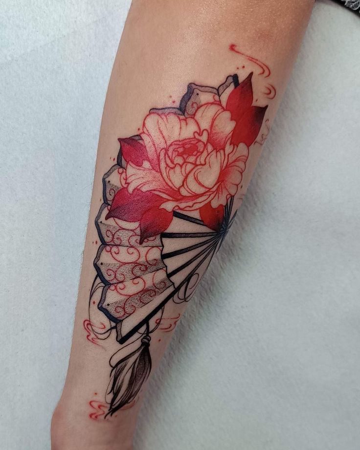 a woman's leg with a flower and fan tattoo on her left calf area