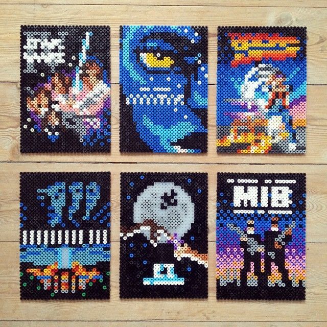 four cross stitch coasters are shown on a wooden surface, each with an image of the same character