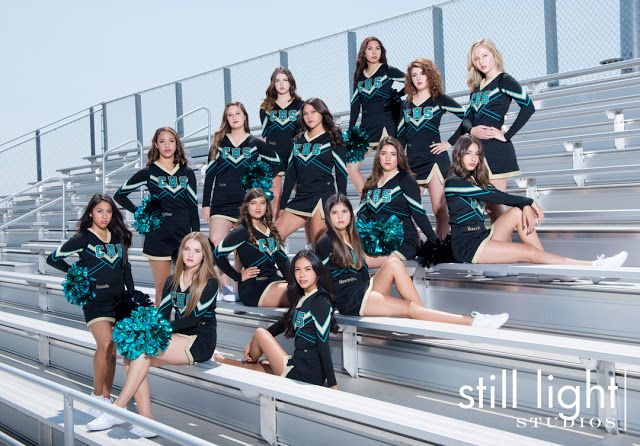 a group of cheerleaders posing for a photo on the bleachers at a football game