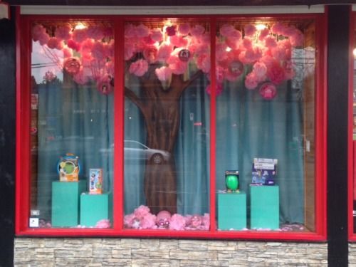 the front window of a flower shop with pink flowers on display in it's windows